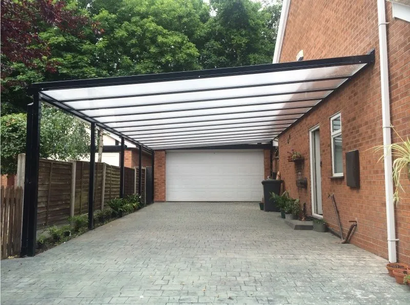 Black aluminium car port/pergola, with polycarbonate roof and garage door in white.
