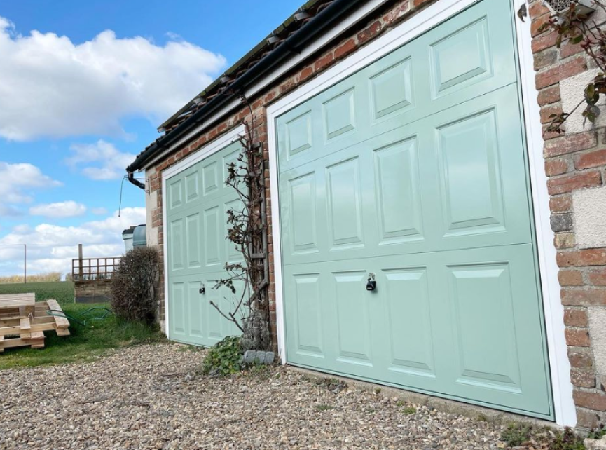 matching chartwell green up and over garage doors with georgian style panel.